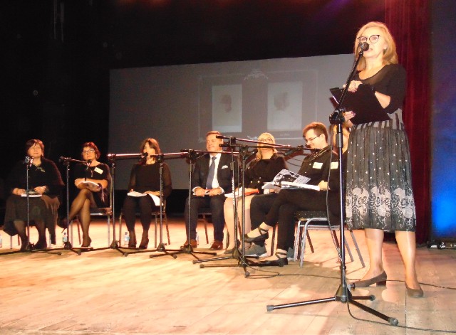 Scena, Kobieta przy mikrofonie, 9 osób ubranych na czarno trzyma tekst, w tle slajd ze zdjęciem Gabrieli Zapolskiej